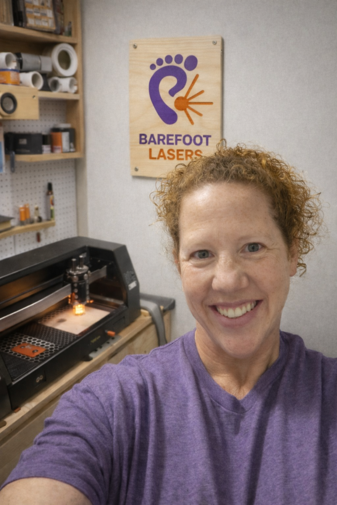 Barefoot Lasers owner & maker smiling in front of work area